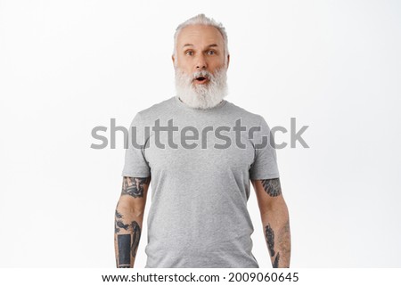 Wow awesome. Impressed mature man with tattoos and beard, drop jaw, gasping and looking in awe and excitement at special promo offer, shopping deal, standing over white background Foto stock © 