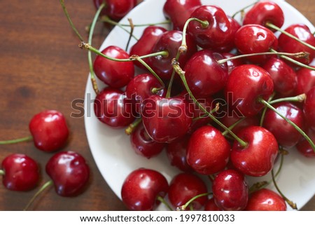 Fresh red cherries fruit on plate on wooden background close up. High quality photo Foto d'archivio © 