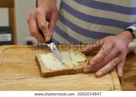 Photo of Woman hands spread bread with butter. High quality photo