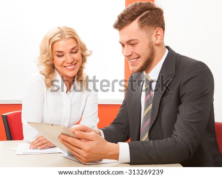 Man and woman working together with tablet in office at desk