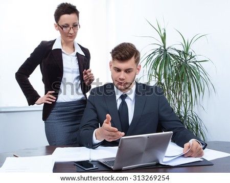 man and woman working together with laptop in office at desk