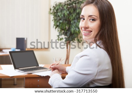 Portrait of happy brown hair woman using laptop in office