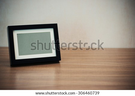 Blank black picture frame at the desk - vintage style effect picture