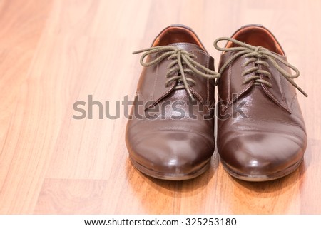 A pair of men\'s brown leather shoes on wooden floor