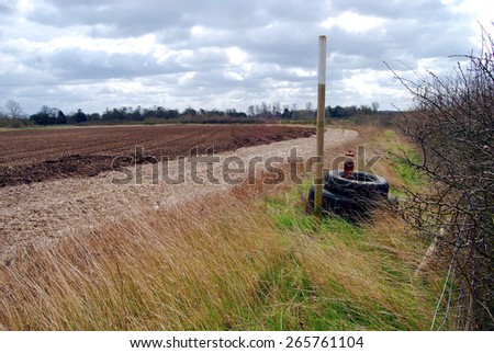 Used Tractor Tyres Looped Over Metal Post, By a Tilled Farmer\'s Field