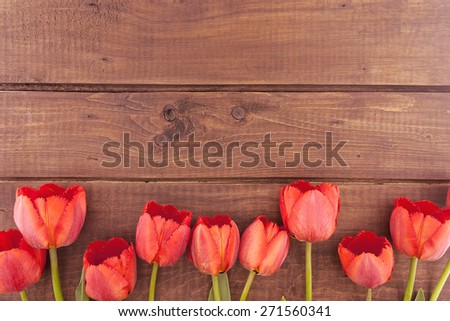 Row of tulips on wooden background with space for message. Mother\'s Day background
