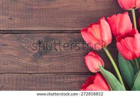 Bouquet of red tulips on wooden background with space for message. Mother\'s Day and spring background.