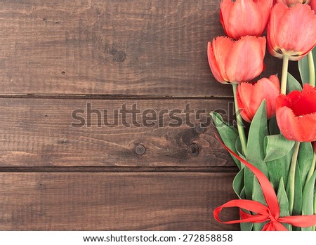 Bouquet of red tulips on wooden background with space for message. Holiday background