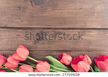 Bouquet of red tulips on a wooden background with space for greeting message. Spring flowers. Spring background.