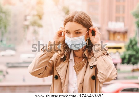 Beautiful stylish girl wear medical face mask on sunny city street. Young elegant happy hipster woman put on protective face mask outdoors. Urban fashion outfit, lifestyle. COVID-19 quarantine, travel Foto d'archivio © 