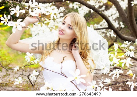 Delicate blonde bride in spring magnolia flowers