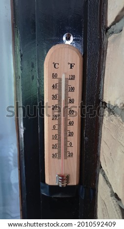 Traditional wall mounted beech wooden thermometer indoor.