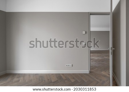 Simple Modern Beige-Grey Wall with grey light switch and grey socket in the Empty Room with open door and oak wood floor. Interior Design Element of contemporary interior design at modern house Сток-фото © 