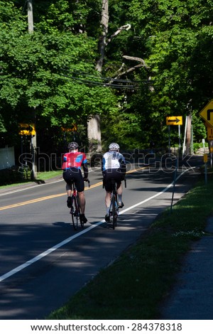 New Canaan, CT, USA - May 24, 2015: Daytime summer time view of people bicycling in the town of New Canaan, Connecticut on May 24, 2015