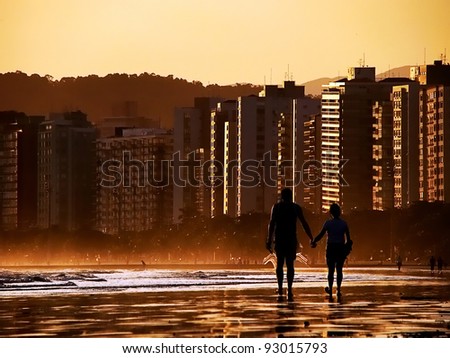 silhouette of couple holding hands walking on the beach