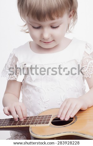 funny beautiful little girl with guitar.musical child playing musical instrument