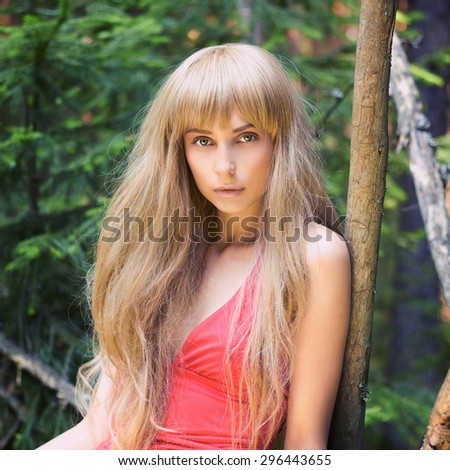 Beautiful Blond Woman in Forest. Summer Beauty blonde Girl in red dress.