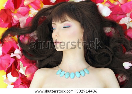 young woman lying on roses petals. beautiful Girl with long hair and Flowers