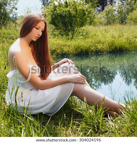 sexy beautiful girl in white dress lowered her feet in the water.nature summer traditional Russian woman