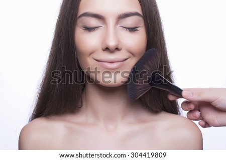 funny smiling beautiful girl with make-up brush.beauty woman Applying Make-up.clean skin cosmetics.Young woman face with perfect skin