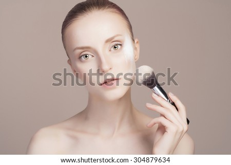 beautiful girl with make-up brush.beauty woman Applying Make-up.clean skin cosmetics.Young woman face with perfect skin