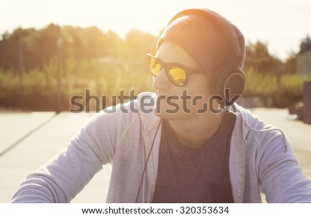 addicted to music young guy listening music with headphones at sunset on outdoors enjoying music .