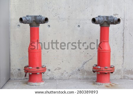 two red fire hydrant poles in front of the wall