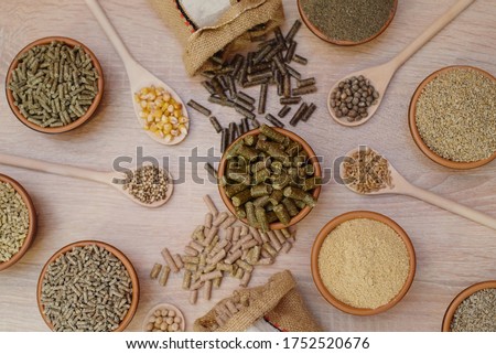 Different kinds of pelleted compound feed in bowls and spoons on wood table, copy space. Top view, flat lay Сток-фото © 