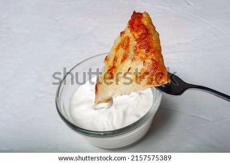 traditional Swiss dish is strung on a fork - part of a potato pancake is strung on a fork and lowered into a saucepan with cream sauce. Imagine de stoc © 