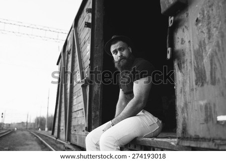 bearded man in the cap posing on the wagon train and travel, black and white