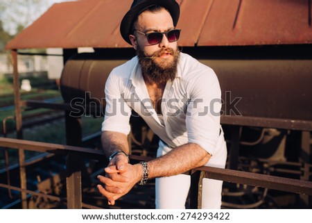bearded man in a sunglasses posing on the old train