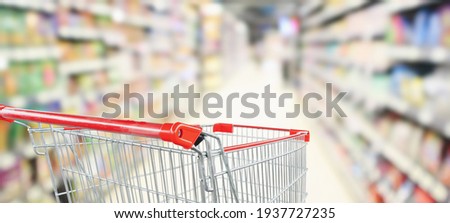 empty red shopping cart in supermarket aisle