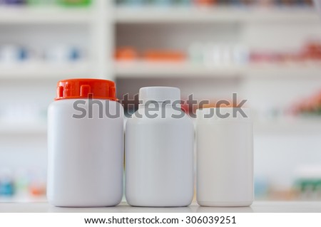Blank white medicine bottles with blur shelves of drug in the pharmacy drugstore background
