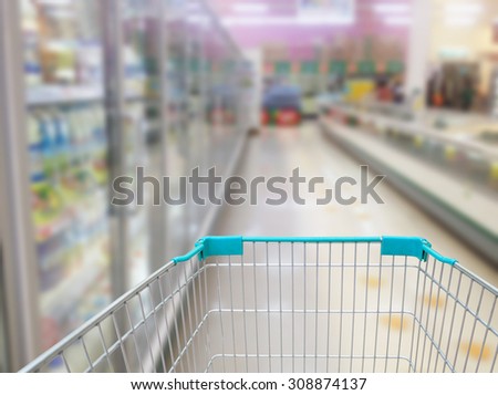 Supermarket Aisle Milk Yogurt Frozen Food Freezer and Shelves blurred background with shopping cart