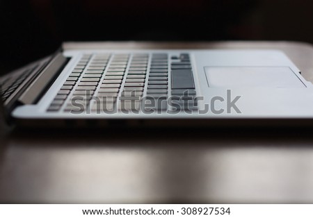 open laptop with black screen on modern wooden desk, angled notebook on table in home interior
