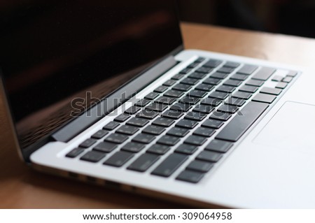 open laptop with black screen on modern wooden desk, angled notebook on table in home interior