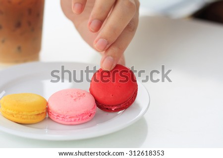woman\'s hand picked a macaron