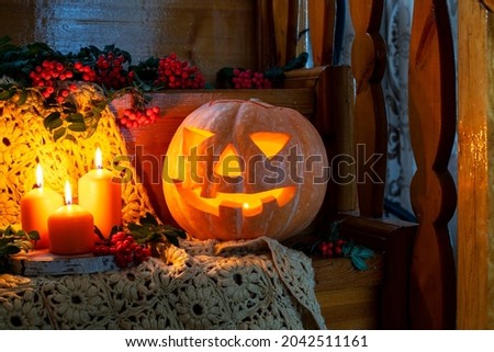 Halloween card. Happy Halloween. Halloween concept in rustic style. Jack's lantern from pumpkin and candles on a wooden staircase. Rowan bunches lie around. Autumn orange concept. 
