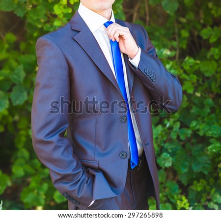 A groom putting on cuff-links as he gets dressed in formal wear .Groom's suit