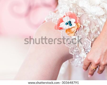 bride dresses garter on the leg.  bride\'s morning