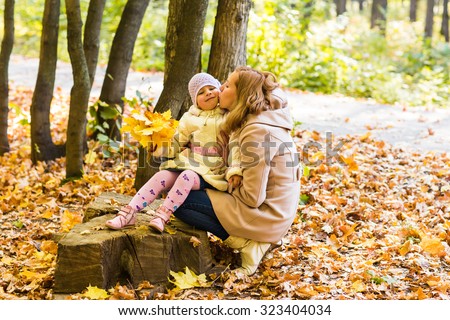 Mother kissing her daughter in the park. Woman kissing her baby girl. Woman with child outdoor in summer park. Happy family playing outdoor