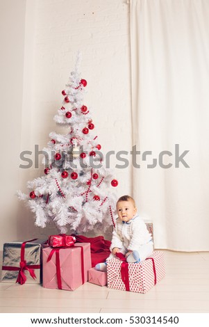 Cheerful Little Baby Boy Playing Near The Christmas Tree Stock Photo