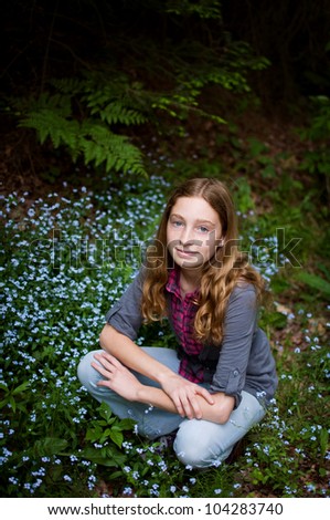 pretty teen girl in a patch of forget-me-not flowers