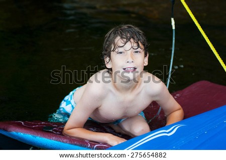 young boy having fun floating on a boogie board in a lake in Haliburton County Ontario