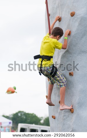 child wearing a harness climbing a rock climbing wall