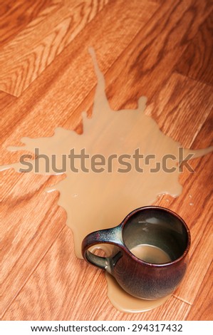 coffee spill on a floor beside a mug