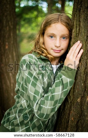 tween girl leaning against a tree outdoors