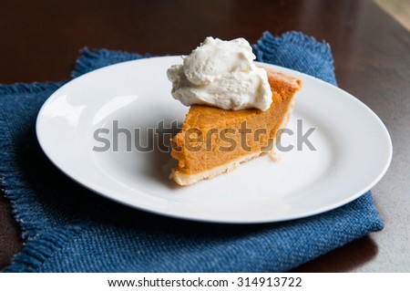 piece of pumpkin pie on a plate with a dollop of whipped cream