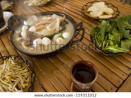 Traditional Chinese meal - different dishes on a bamboo table. Quail egg stew as main dish.