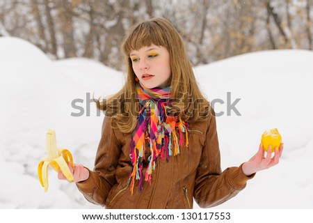 Smiling girl with color scarf holding banana and lemon